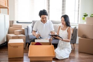 Young couple packing boxes and looking at moving checklist