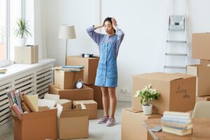 Woman standing with her hands on her head in stress, surrounded by moving boxes